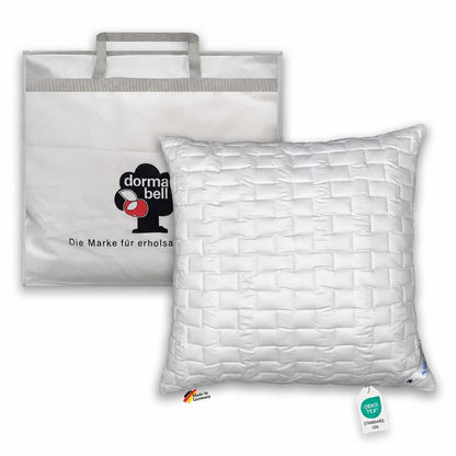 Weißes Kopfkissen 80x80 cm dormabell Active fresh mit rechteckiger Steppung, aufrecht vor einer Tragetasche.
