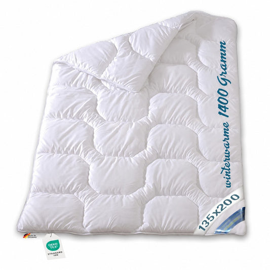 Weiße Garanta Winterbettdecke 135x200 cm, extra warm mit Klimafaser und Wellensteppung, mit Schriftzug „winterwarme 1400 Gramm“.       